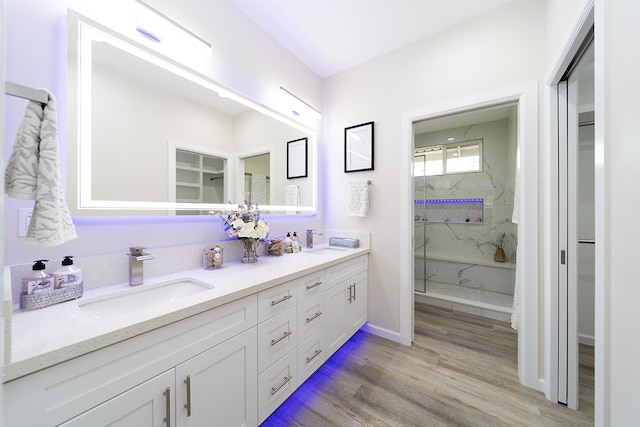 bathroom featuring wood-type flooring, tiled shower, and vanity