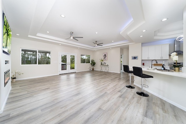 workout room with french doors, a raised ceiling, and light hardwood / wood-style flooring