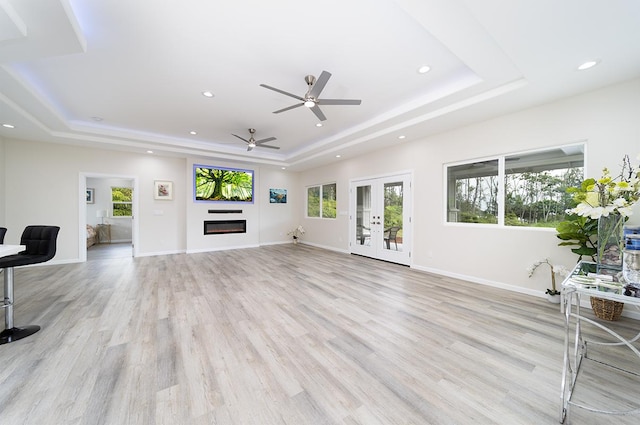 living room featuring french doors, light hardwood / wood-style floors, and a tray ceiling