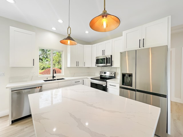 kitchen with light stone counters, white cabinetry, stainless steel appliances, and sink