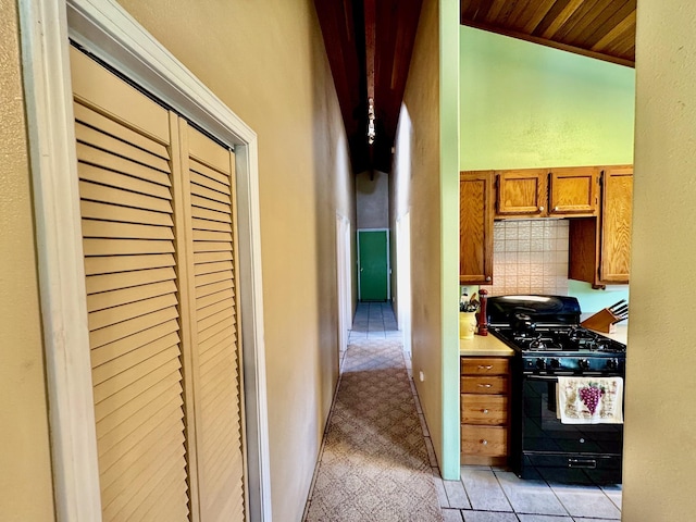 kitchen featuring lofted ceiling, black gas stove, wooden ceiling, decorative backsplash, and light colored carpet