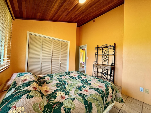 tiled bedroom featuring crown molding, vaulted ceiling, a closet, and wooden ceiling