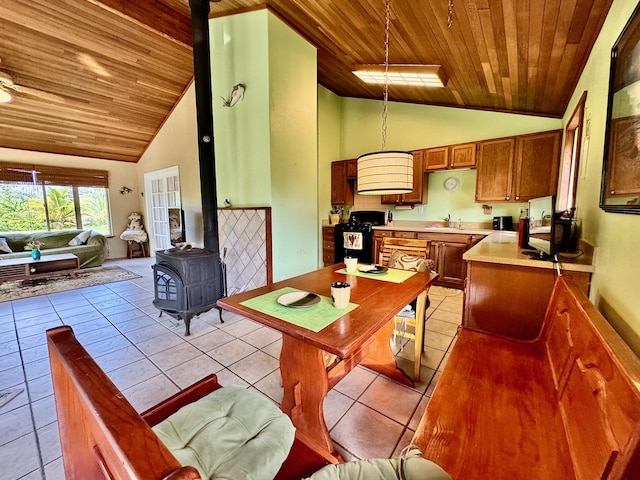 kitchen with sink, decorative light fixtures, high vaulted ceiling, and a wood stove