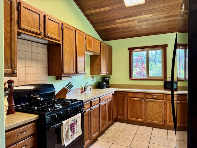 kitchen featuring vaulted ceiling, tasteful backsplash, sink, light tile patterned floors, and black gas range