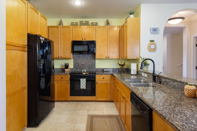 kitchen with sink, dark stone countertops, and black appliances