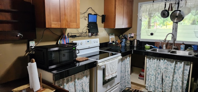 kitchen featuring white electric range oven, a sink, black microwave, and brown cabinets