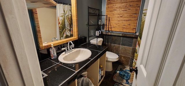 bathroom featuring toilet, tile walls, and vanity