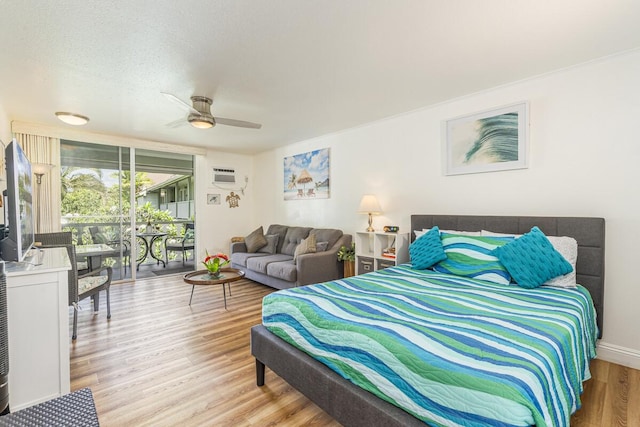 bedroom with access to exterior, ceiling fan, a wall mounted air conditioner, wood finished floors, and a textured ceiling