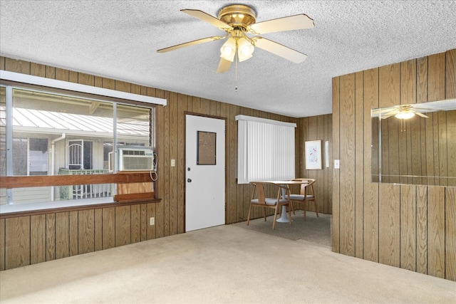 interior space with cooling unit, ceiling fan, wooden walls, and carpet floors