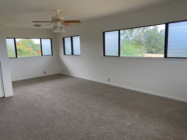 carpeted spare room featuring a healthy amount of sunlight and ceiling fan