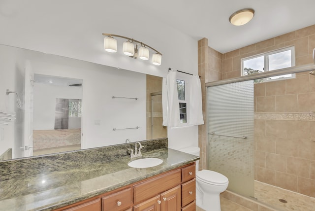 bathroom with vanity, a shower with shower door, tile patterned floors, and toilet