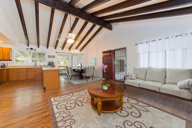 living room featuring an inviting chandelier, beam ceiling, high vaulted ceiling, and light wood-type flooring