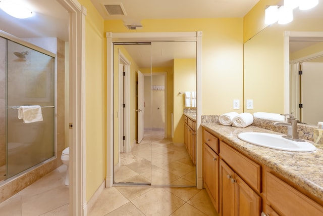 bathroom with vanity, a shower with door, tile patterned floors, and toilet