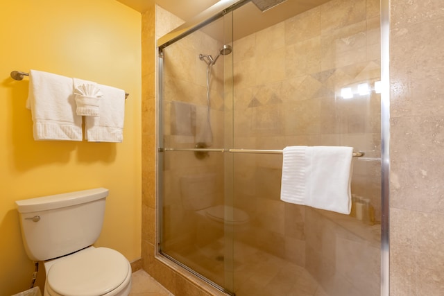 bathroom with tile patterned flooring, toilet, and a shower with shower door