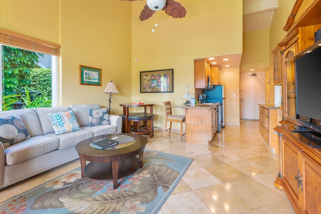 living room with ceiling fan, light tile patterned floors, and a high ceiling