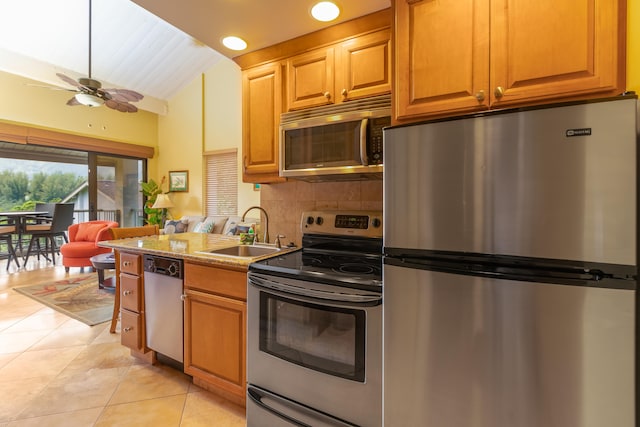 kitchen featuring lofted ceiling, sink, tasteful backsplash, light tile patterned floors, and stainless steel appliances