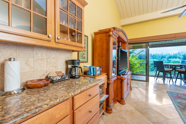 kitchen featuring backsplash, light tile patterned floors, and light stone countertops