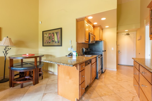 kitchen featuring stainless steel appliances, light tile patterned flooring, a breakfast bar area, and light stone counters