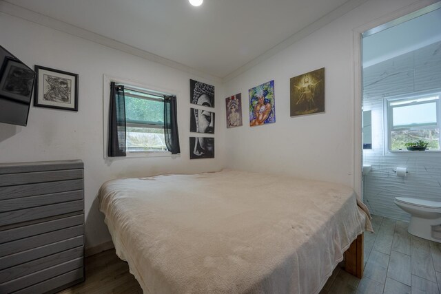 bedroom featuring crown molding, dark hardwood / wood-style floors, and multiple windows