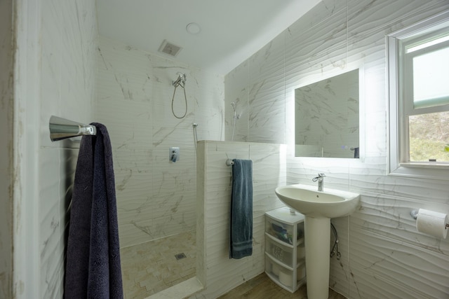 bathroom featuring a tile shower and tile walls