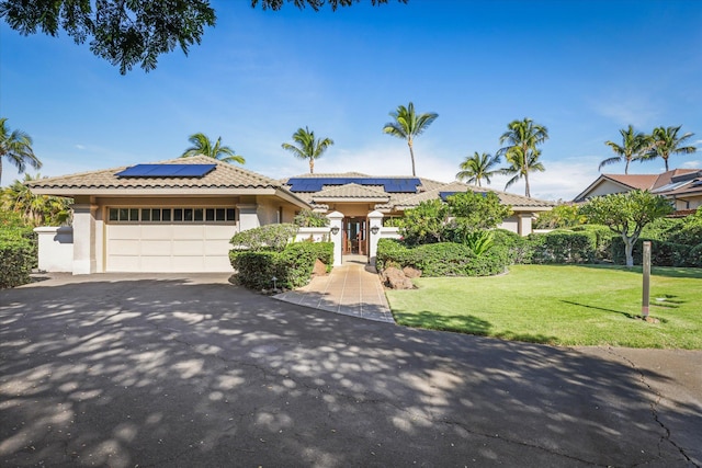 view of front of house featuring a garage, a front yard, and solar panels