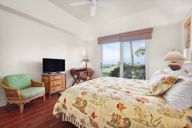 bedroom featuring ceiling fan, a tray ceiling, dark hardwood / wood-style flooring, and access to outside