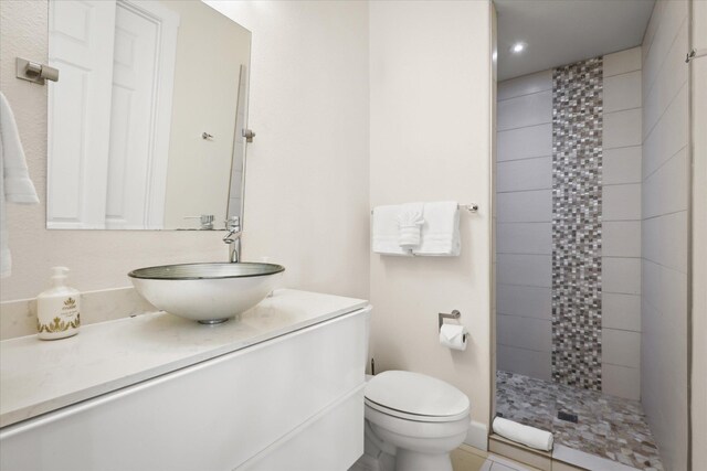 bathroom featuring vanity, tiled shower, and toilet