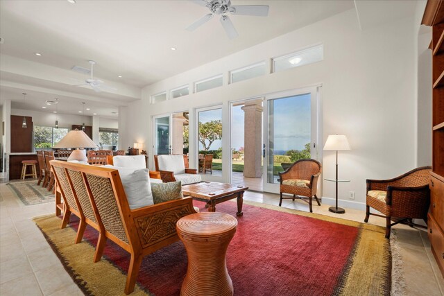 living room with ceiling fan, light tile patterned floors, a healthy amount of sunlight, and a towering ceiling