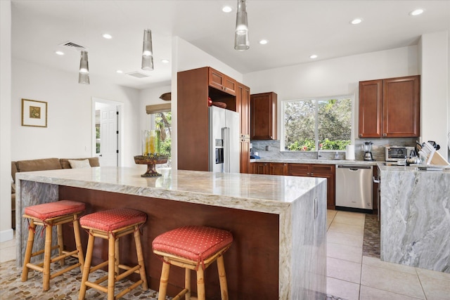 kitchen featuring a healthy amount of sunlight, stainless steel appliances, a kitchen breakfast bar, and a kitchen island