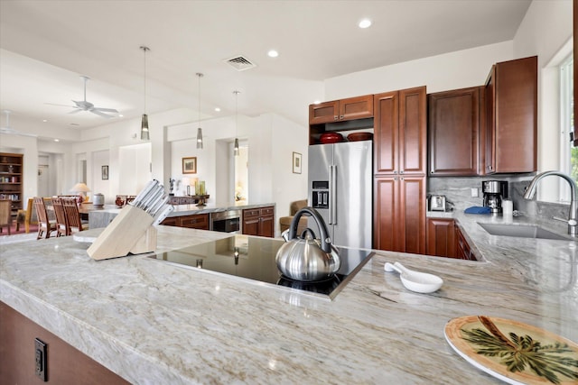 kitchen featuring sink, high end refrigerator, decorative light fixtures, black electric cooktop, and light stone countertops