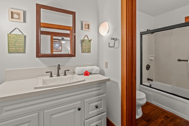 full bathroom featuring hardwood / wood-style flooring, vanity, combined bath / shower with glass door, and toilet