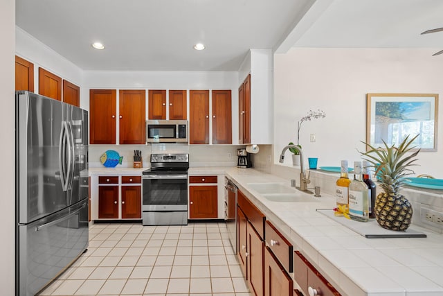 kitchen featuring appliances with stainless steel finishes, sink, light tile patterned floors, and tile counters