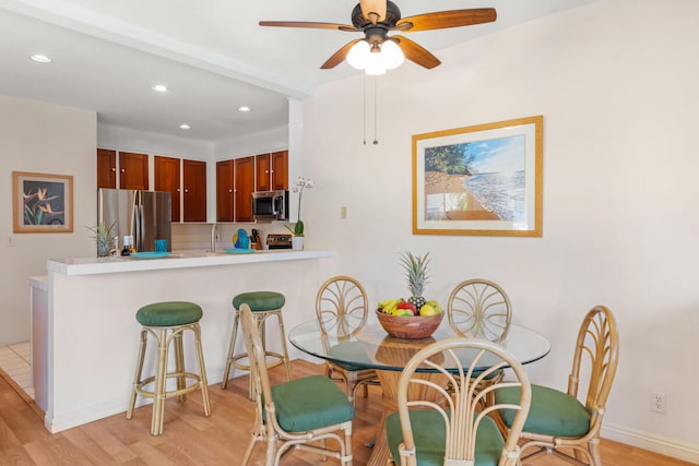 dining room with sink, ceiling fan, and light wood-type flooring