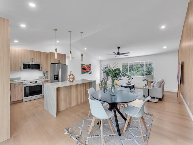 kitchen featuring decorative light fixtures, stainless steel appliances, light hardwood / wood-style floors, and a kitchen island