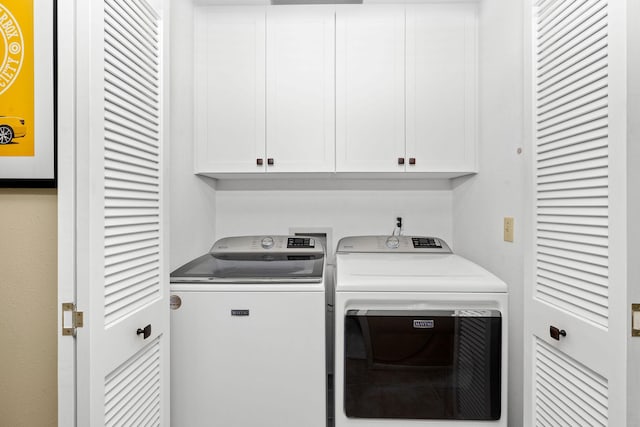 clothes washing area with cabinets and washer and dryer