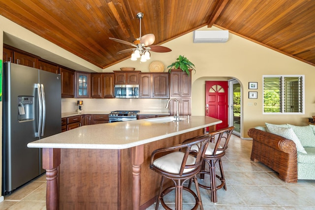 kitchen with stainless steel appliances, a large island with sink, lofted ceiling with beams, and an AC wall unit