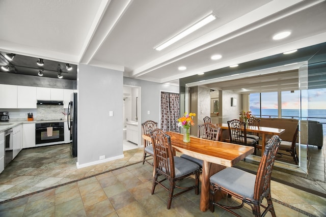 dining room with a water view and beam ceiling