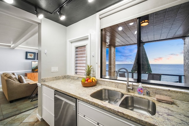 kitchen with sink, a water view, stainless steel dishwasher, light stone countertops, and white cabinets