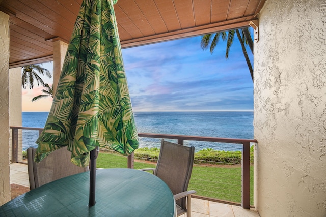 balcony at dusk featuring a water view