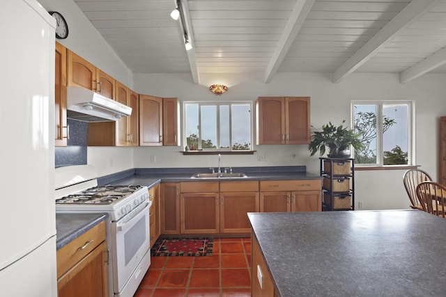 kitchen featuring rail lighting, sink, dark tile patterned floors, beamed ceiling, and white appliances