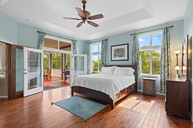 bedroom with hardwood / wood-style flooring, access to outside, ceiling fan, a raised ceiling, and french doors