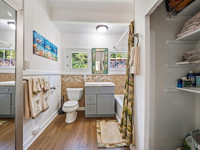 bathroom featuring toilet, tile walls, vanity, a bathtub, and hardwood / wood-style floors