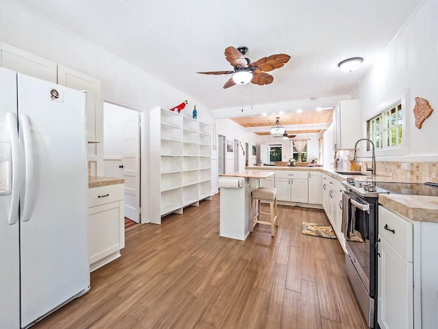 kitchen featuring a breakfast bar, white cabinetry, electric range, kitchen peninsula, and white fridge with ice dispenser