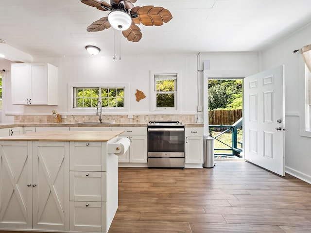 kitchen featuring sink, white cabinetry, tasteful backsplash, light hardwood / wood-style flooring, and stainless steel range