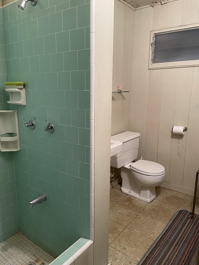 bathroom with wooden walls, tiled shower, and toilet