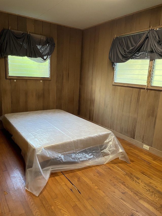 bedroom with hardwood / wood-style floors and wood walls