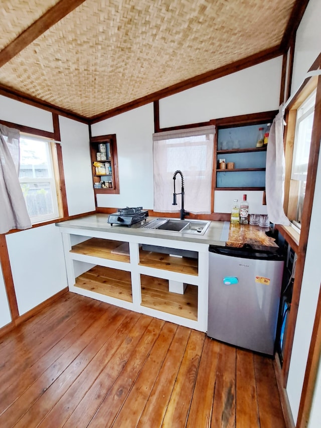 kitchen featuring wood-type flooring, stainless steel fridge, and sink