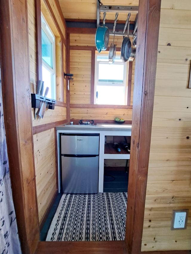 kitchen with hanging light fixtures, stainless steel refrigerator, and wooden walls