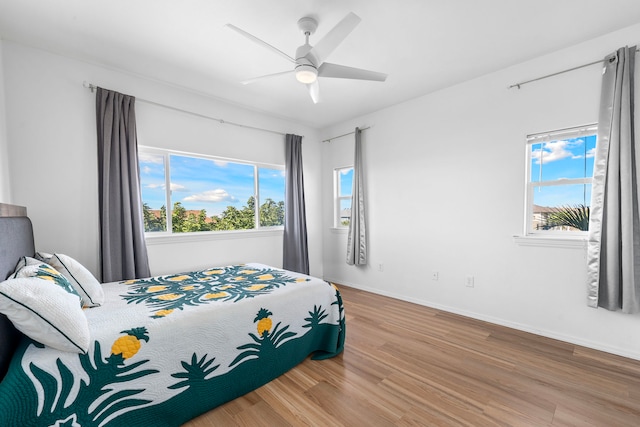 bedroom featuring hardwood / wood-style flooring, ceiling fan, and multiple windows