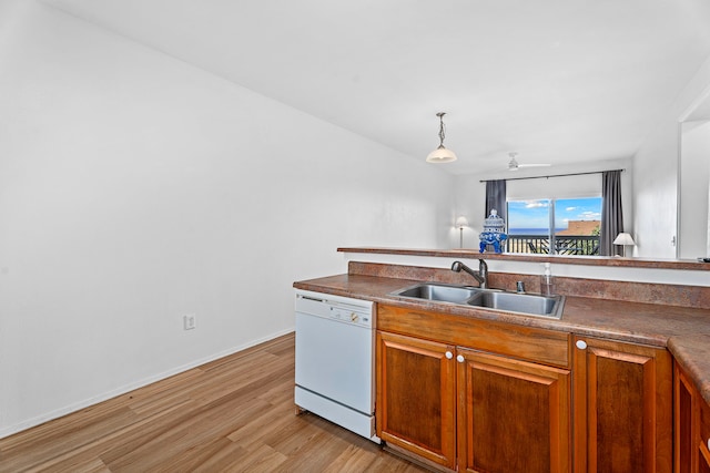 kitchen with dishwasher, sink, pendant lighting, and light hardwood / wood-style flooring